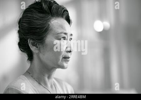 head shot portrait of a sad asian old woman, side view, black and white Stock Photo