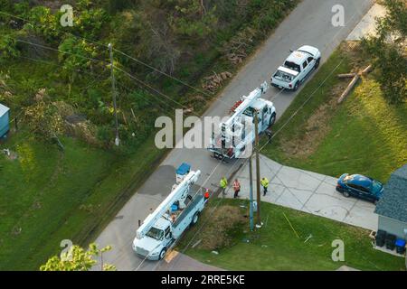 Electrician workers repairing damaged power lines using bucket trucks after hurricane Ian in Florida residential area Stock Photo