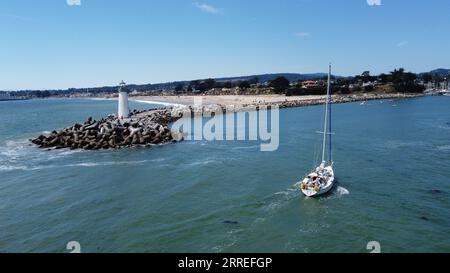 Lighthouse With Sailboat Stock Photo