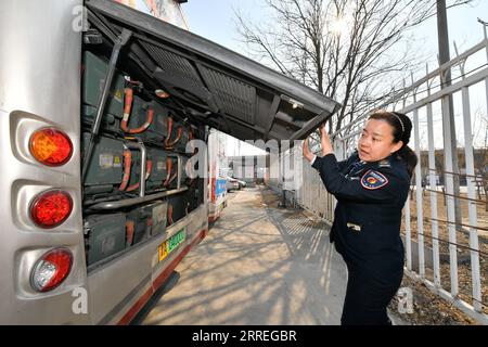 220228 -- TIANJIN, Feb. 28, 2022 -- Wang Yan checks the batteries of her bus at a bus stop in north China s Tianjin, Feb. 24, 2022. Tianjin bus driver Wang Yan is a National People s Congress NPC deputy. Since taking on her duties in 2018, Wang has continued to submit suggestions to the NPC, covering a variety of areas, such as transportation and health care. As a bus driver, she makes the most of her job, listening to her passengers opinions, while formulating suggestions that can have an influence on government policies. This year is the last year of her term of NPC deputy, Wang will put for Stock Photo
