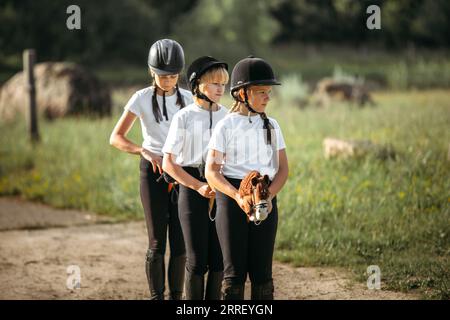 Girls jockeys sitting on toy horses walk along the road and work out a step. Stock Photo