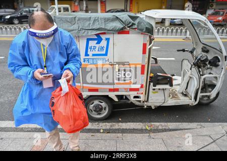 220326 -- QUANZHOU, March 26, 2022 -- A courier contacts a resident over the phone to fulfil an online order in Quanzhou, southeast China s Fujian Province, March 26, 2022. More than 100 local express delivery couriers have volunteered to deliver goods for residents amid the recent COVID-19 resurgence in Quanzhou. Photo by /Xinhua CHINA-FUJIAN-QUANZHOU-COVID-19-VOLUNTEER COURIERS CN ZhouxYi PUBLICATIONxNOTxINxCHN Stock Photo