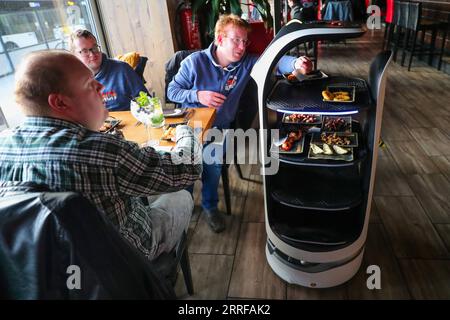 220410 -- SINT-NIKLAAS, April 10, 2022 -- A customer takes the dishes served by a robot at a restaurant in Sint-Niklaas, East Flanders, Belgium, April 9, 2022. Two service robots, designed and manufactured in China, became the stars of a restaurant in Sint-Niklaas in Belgium. They not only reduced the cost for the restaurant, but also won popularity among the customers.  BELGIUM-SINT-NIKLAAS-RESTAURANT-ROBOT ZhengxHuansong PUBLICATIONxNOTxINxCHN Stock Photo