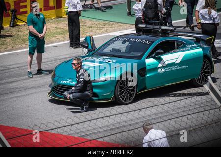 Captured moments before the race, Bernd Maylander, the official F1 Safety Car driver, kneeling beside the iconic Aston Martin Safety Car. Stock Photo