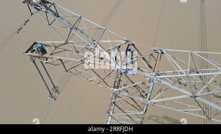 220419 -- HEFEI, April 19, 2022 -- Aerial photo taken on April 19, 2022 shows workers maintaining the Longquan-Zhengping 500-kilovolt direct current transmission project in Lujiang County of Hefei, east China s Anhui Province. In Lujiang of east China s Anhui Province, a team of utility technicians works like spidermen to maintain the 500-kilovolt direct current transmission project expanding from Longquan to Zhengping. The power line passing Anhui is one of the key channels transmitting over 10 billion kWh of electricity per year, all-clean hydropower, from the Three Gorges hydropower station Stock Photo