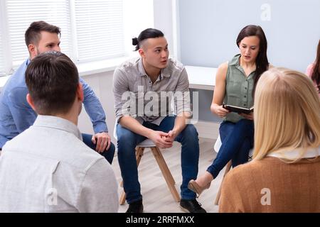 Young Multiracial Millennial Friends Sitting In Circle Having Group Discussion Stock Photo