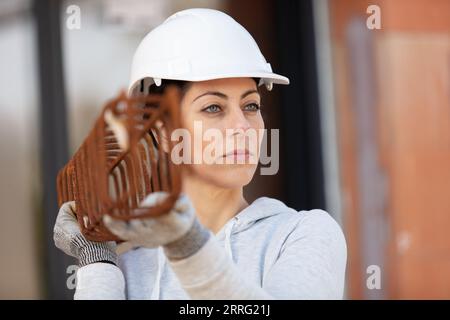 female builder holding metal tray at construction site Stock Photo