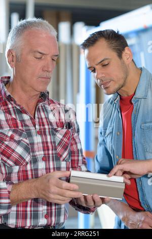 two men inspecting vats in a modern winemaking factory Stock Photo