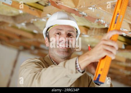 male construction worker using level to measure grade of ceiling Stock Photo