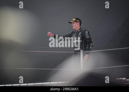 George Russell stands at the podium, reveling in his third-place finish at the Spanish Grand Prix. Stock Photo