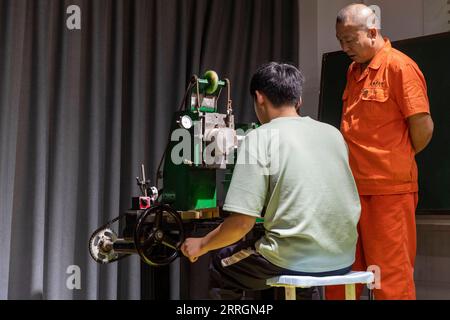 220527 -- XINMI, May 27, 2022 -- Cheng Yucai R guides an apprentice to operate a Guilloche machine at his workshop in Xinmi City, central China s Henan Province, on May 24, 2022. Guilloche is a decorative technique in which a precise, intricate and repetitive pattern is mechanically engraved into a material via engine turning. The technique uses a machine controlled by the delicacy of the hand of craftsman. As an important process in making superior watch and jewelry, the art is now mastered by rarely few people. Cheng Yucai, born in 1978, got to know Guilloche in 2013 when he saw a cigarette Stock Photo