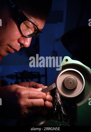 220527 -- XINMI, May 27, 2022 -- Cheng Yucai grinds tools at his workshop in Xinmi City, central China s Henan Province, on May 24, 2022. Guilloche is a decorative technique in which a precise, intricate and repetitive pattern is mechanically engraved into a material via engine turning. The technique uses a machine controlled by the delicacy of the hand of craftsman. As an important process in making superior watch and jewelry, the art is now mastered by rarely few people. Cheng Yucai, born in 1978, got to know Guilloche in 2013 when he saw a cigarette case decorated with the technique. He was Stock Photo