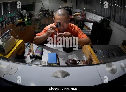 220527 -- XINMI, May 27, 2022 -- Cheng Yucai checks a processed dial at his workshop in Xinmi City, central China s Henan Province, on May 24, 2022. Guilloche is a decorative technique in which a precise, intricate and repetitive pattern is mechanically engraved into a material via engine turning. The technique uses a machine controlled by the delicacy of the hand of craftsman. As an important process in making superior watch and jewelry, the art is now mastered by rarely few people. Cheng Yucai, born in 1978, got to know Guilloche in 2013 when he saw a cigarette case decorated with the techni Stock Photo