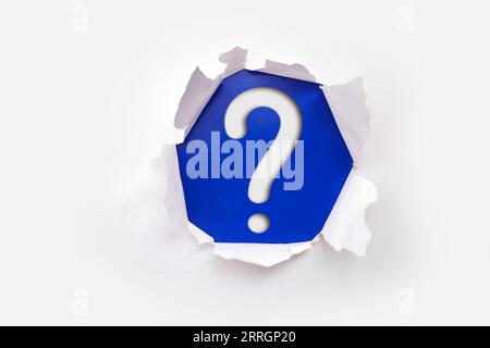 Torn out white paper with question mark symbol. White torn paper revealing question mark symbol on Pink paper. Stock Photo