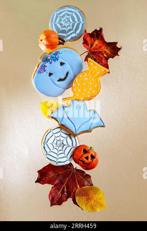 Painted Halloween gingerbread and autumn leaves on a beige background. Levitation. Stock Photo