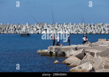 220620 -- ALEXANDRIA, June 20, 2022 -- People standing on concrete barriers used against sea-level rises fish by the sea in Alexandria, Egypt, June 19, 2022. The Egyptian Ministry of Water Resources and Irrigation has launched a climate adaptation project on the North Coast and the Nile Delta to counter sea-level rises, the impact of weather hazards on low-lying coastal areas, and seawater intrusion.  EGYPT-ALEXANDRIA-CLIMATE CHANGE-RISING SEA LEVEL-COASTAL CONCRETE BARRIER AhmedxGomaa PUBLICATIONxNOTxINxCHN Stock Photo