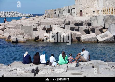 220620 -- ALEXANDRIA, June 20, 2022 -- People sit on the concrete barriers used against sea-level rises in Alexandria, Egypt, June 19, 2022. The Egyptian Ministry of Water Resources and Irrigation has launched a climate adaptation project on the North Coast and the Nile Delta to counter sea-level rises, the impact of weather hazards on low-lying coastal areas, and seawater intrusion.  EGYPT-ALEXANDRIA-CLIMATE CHANGE-RISING SEA LEVEL-COASTAL CONCRETE BARRIER AhmedxGomaa PUBLICATIONxNOTxINxCHN Stock Photo