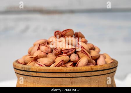 Pistachios in wooden bowl. Pistachios on white wood background. Close up Stock Photo