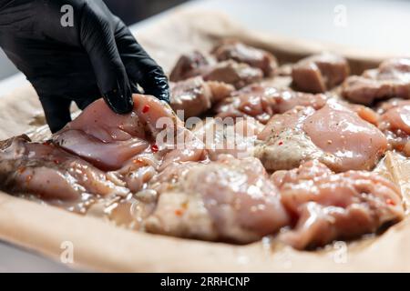 hand puts raw chicken fillet meat on pan before cooking in oven at home Stock Photo