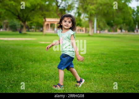 Happy cute little indian girl child having fun at summer park or garden. Stock Photo