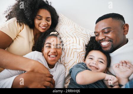 Mom, dad and kids in bed with tickling, comic joke and laugh with bonding, care and love in family home. Black man, mother and daughter with smile Stock Photo