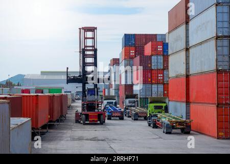 Container forklift and truck with stack of containers as background, container boxes, logistics transportation industry concept. Stock Photo