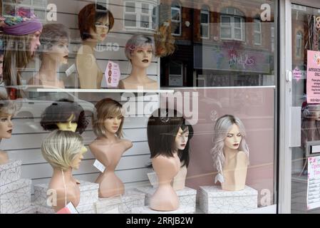 Hairdressers or Hairdresser Shop Window, Display Window or Store Window with Display of Mannequins or Dummies with Wigs and Topknots West Kirby E Stock Photo
