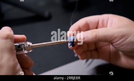 An engineer connects two parts of a radio circuit with a soldering iron. Stock Photo