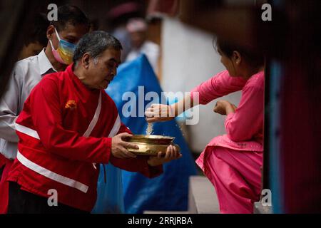 220805 -- KATHMANDU, Aug. 5, 2022 -- A Buddhist distributes an offering during the Pancha Dan festival in Kathmandu, Nepal, Aug. 5, 2022. Pancha Dan, the festival of five summer gifts, is observed by the Buddhists by giving away five elements including wheat grains, rice grains, salt, money and fruit.  NEPAL-KATHMANDU-PANCHA DAN FESTIVAL SulavxShrestha PUBLICATIONxNOTxINxCHN Stock Photo