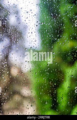 Water drops on window glass with blur garden background Stock Photo