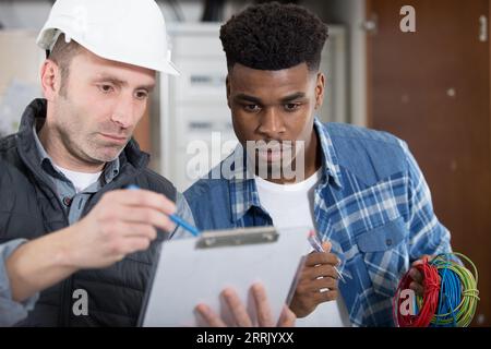 two workers in uniform smiling and holding clipboards Stock Photo