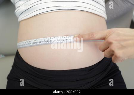 gynecologist doctor uses a measuring tape on pregnant belly Stock Photo