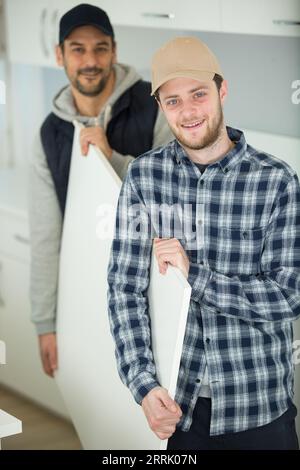 senior and junior carpenter carrying wooden planks at construction site Stock Photo