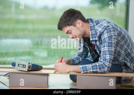 young male fitter measuring floorboard Stock Photo