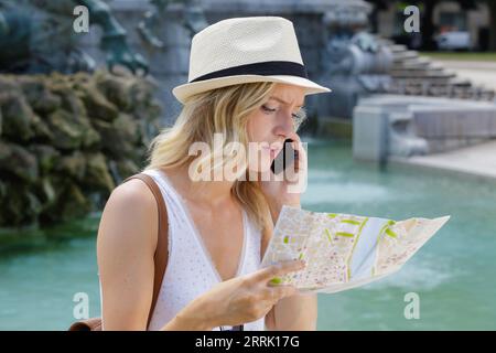 young female tourist looking at map and talking on telephone Stock Photo