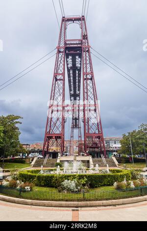 Plaza Puente with a fountain and Vizcaya Bridge, world's oldest transporter bridge linking the towns of Portugalete and Getxo in Biscay, Spain. Stock Photo