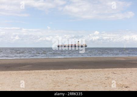 Large cargo ship sailing on the North sea in Germany. View from the beach. Stock Photo