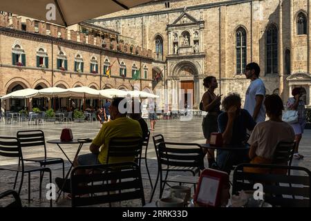 Piazza del Popolo, the arcades with bars and restaurants crowded with tourists on a hot late summer day. Ascoli Piceno, Marche region, Italy, Europe Stock Photo