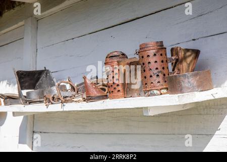Old rusty beekeeping tools on outdoor shelf Stock Photo