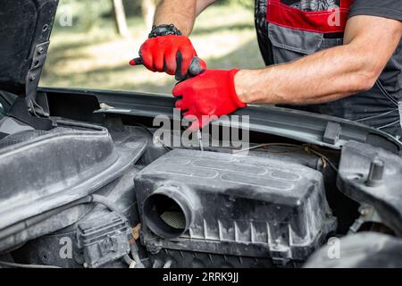 Car repair. An auto mechanic opens the air filter housing of an internal combustion engine. Stock Photo