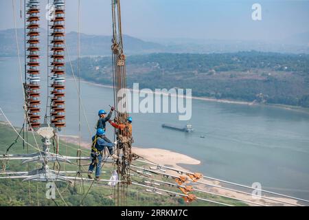 220913 -- CHONGQING, Sept. 13, 2022 -- Technicians work during the cross-Yangtze River wiring operation for the Baihetan-Zhejiang 800 kv ultra-high voltage direct current UHVDC transmission line project Chongqing section in southwest China s Chongqing, Sept. 13, 2022. After a 13-day campaign, the cross-Yangtze River wiring operation for the Baihetan-Zhejiang 800 kv ultra-high voltage direct current UHVDC transmission line project concluded successfully on Tuesday. The 2,140-kilometer line, whose construction kicked off in October 2021, winds its way through Sichuan, Chongqing, Hubei, Anhui and Stock Photo