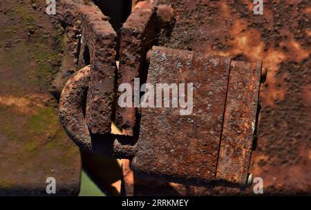 Rusted lock on a rusty metal post. Isolated closeup corroded padlock, iron oxide corrosion process detailed image. Stock Photo