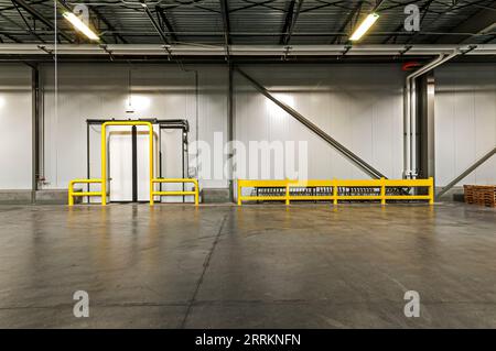 Sliding door to freezer from loading dock in a new cold-storage facility.  Yellow guardrails around doors, and fluid piping to warm floors. Stock Photo