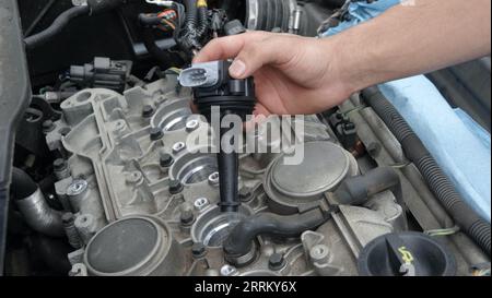 Vista, CA USA -September 3, 2023: Close up of hand inserting new ignition coil into engine Stock Photo