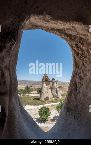 typical fairy chimney view from inside an dug out cave, geological formation of eroded rock, in the open air museum of Goreme, in Cappadocia, Turkey, Stock Photo