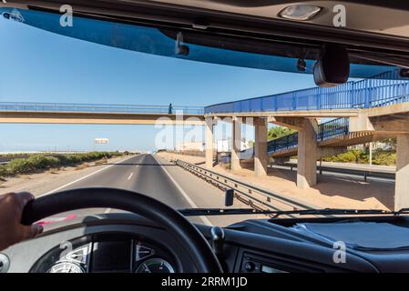 View from the driving position of a truck of a pedestrian walkway where a person crosses on a highway. Stock Photo