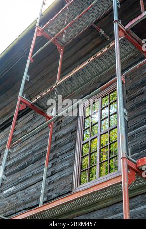 Renovation of an old historic wooden church. Scaffolding set up against the wall of the building Stock Photo