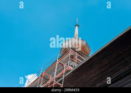 Renovation of an old historic wooden church. Scaffolding erected next to the church tower. Stock Photo