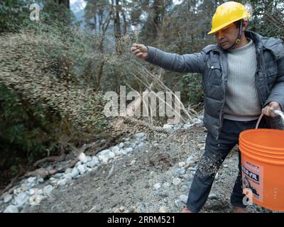 221001 -- LHASA, Oct. 1, 2022 -- A worker sows seeds near the highway linking Pad Township in the city of Nyingchi and Medog County, southwest China s Tibet Autonomous Region, March 11, 2021. The 67.22-km road connects Pad Township in the city of Nyingchi and Medog County. It is the second passageway to Medog, following the first one connecting the county and Zhamog Township, Bomi County. After the new highway opens to traffic, the length of the road connecting the city proper of Nyingchi and Medog County will be shortened to 180 km from 346 km, cutting travel time to four hours. Photo by /Xin Stock Photo