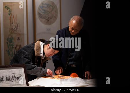221121 -- ZHENGZHOU, Nov. 21, 2022 -- Li Renqing instructs his apprentice to apply ink onto rubbing paper at an exhibition hall of Zhengzhou Shang Dynasty Ruins Museum in Zhengzhou, central China s Henan Province, Nov. 17, 2022. Making rubbings for tablet inscriptions is a craft with a history of over 1,000 years in China, invented as a way to copy documents even before the art of printing. Upgrading the traditional rubbing craft which can only be applied to flat surface, Li Renqing, born in 1963 in Xinyang of central China s Henan Province, has been working for a whole life on rubbings of hig Stock Photo